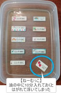 お名前シールの油実験10分経過画像。ねーむっこのお名前シールが浮いてしまう。